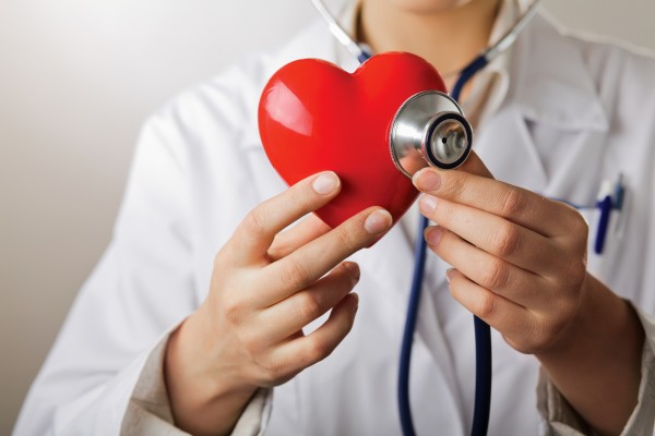 A doctor with stethoscope examining red heart